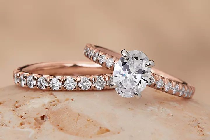 A rose gold, oval diamond engagement ring and matching wedding band